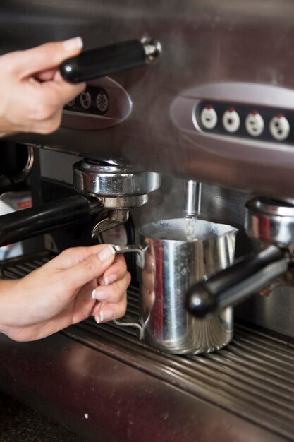 Barista che prende acqua calda dal rubinetto nella tazza