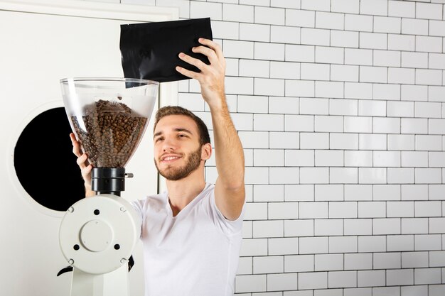 Barista che versa i chicchi di caffè nella macchina del caffè