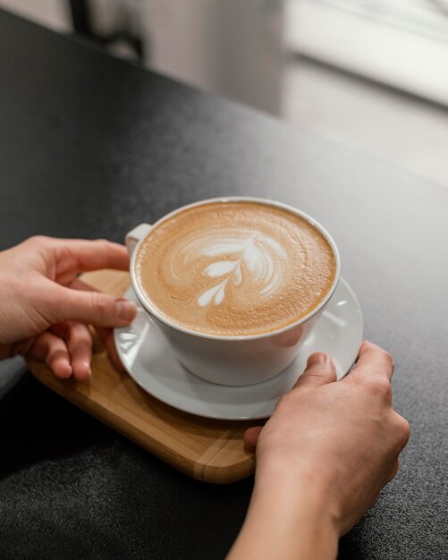 Barista femminile che mette la tazza di caffè decorata sul bancone