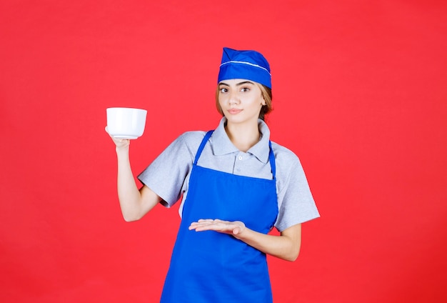 Barista femminile che tiene una tazza grande bianca