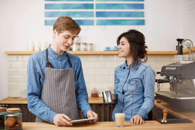 Barista femminile piacevole che produce il caffè del raf che sorride allegramente, sembrante felice.