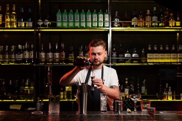 Barista maschio che prepara un cocktail con uno shaker