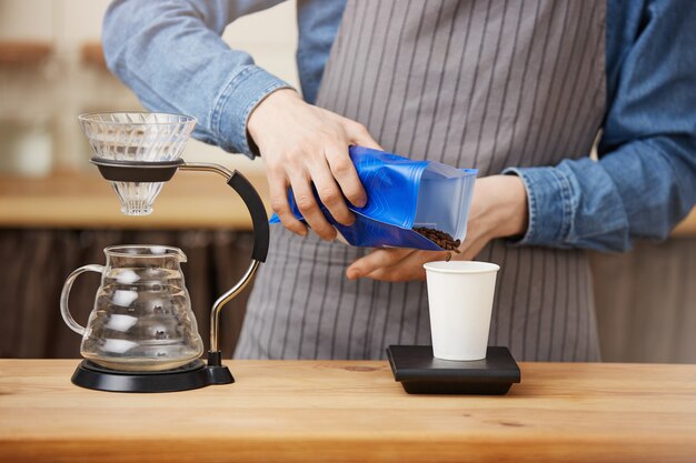 Barista maschio che produce il caffè del pouron, ridimensionamento del caffè con la scala digitale.