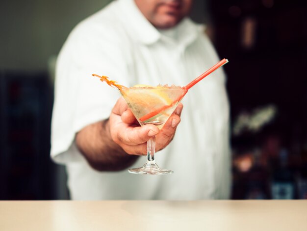 Barista maschio che serve cocktail nel bicchiere da martini