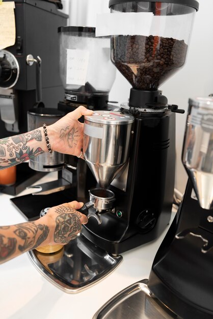 Barista maschio con tatuaggi al lavoro usando la macchina del caffè