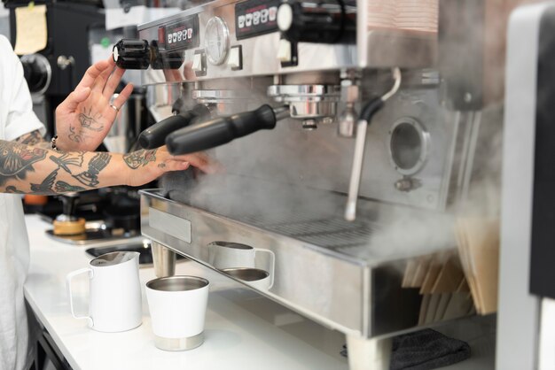 Barista maschio con tatuaggi usando la macchina del caffè al bar