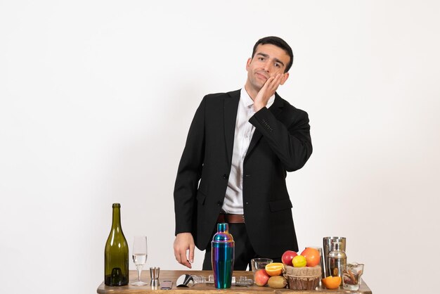 Barista maschio vista frontale in piedi davanti al tavolo con bevande in posa sulla scrivania bianca notte drink club alcol bar