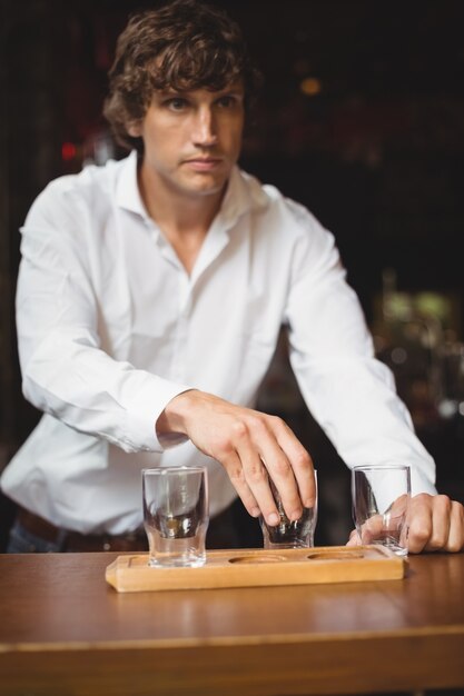 Barista organizzando il bicchiere di birra sul vassoio al bancone del bar