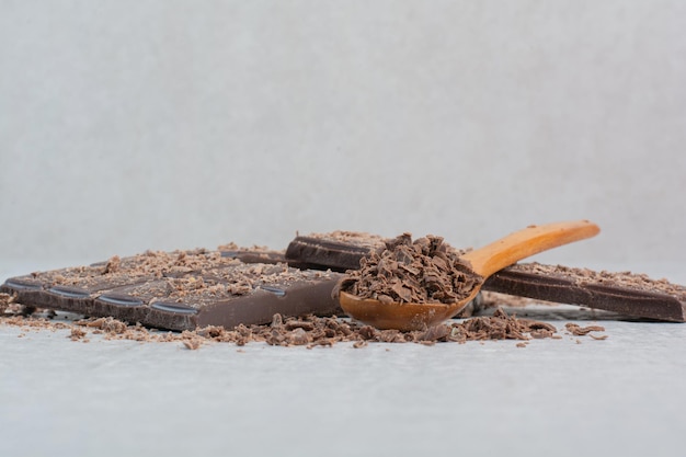 Barretta di cioccolato con cucchiaio e cacao su sfondo grigio. Foto di alta qualità