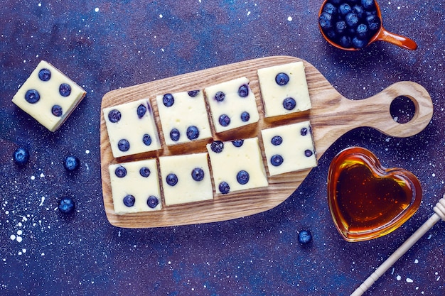 Barrette di cheesecake ai mirtilli con miele e frutti di bosco freschi.