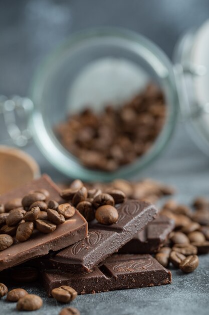 Barrette di cioccolato con chicchi di caffè su grigio.