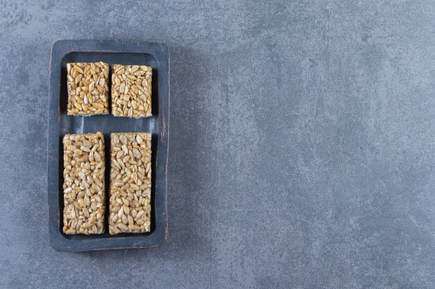 Barrette di muesli in un piatto di legno sulla superficie di marmo