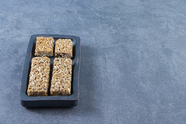 Barrette di muesli in un piatto di legno, sullo sfondo di marmo.