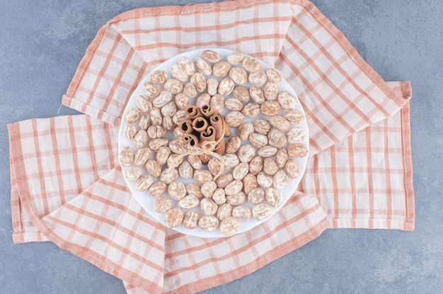 Bastoncini di cannella e biscotti sull'asciugamano, sullo sfondo di marmo.