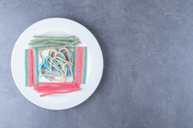 Bastoncini di caramelle dolci sul piatto di legno sul tavolo di marmo.