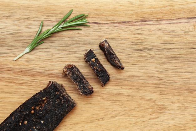 Bastoncino a fette di biltong snack e condimento al rosmarino su una superficie di legno
