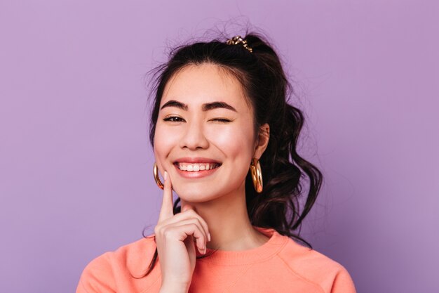 Beata donna asiatica con capelli ricci facendo facce buffe. Studio shot di felice coreano giovane donna.