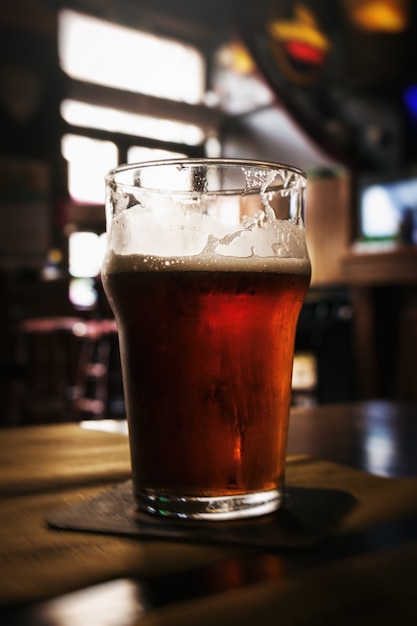 Bel bicchiere di birra scura e gustosa fredda in bar. Sfondo scuro.