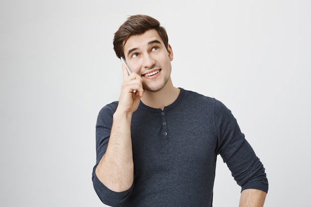 Bel giovane uomo parlando al telefono e alzando lo sguardo