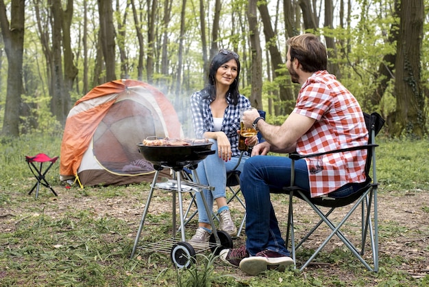 Bel maschio felice che prepara barbecue all'aperto mentre beve birra