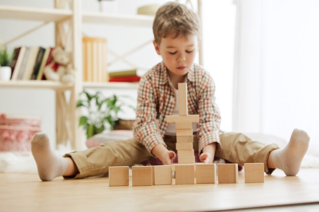 Bel ragazzo che gioca con i cubi di legno a casa