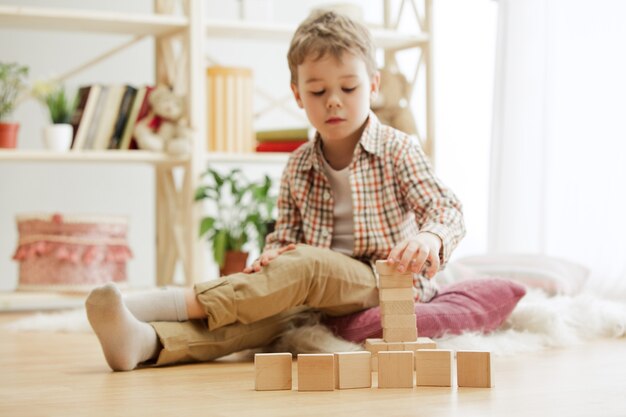 Bel ragazzo che gioca con i cubi di legno a casa