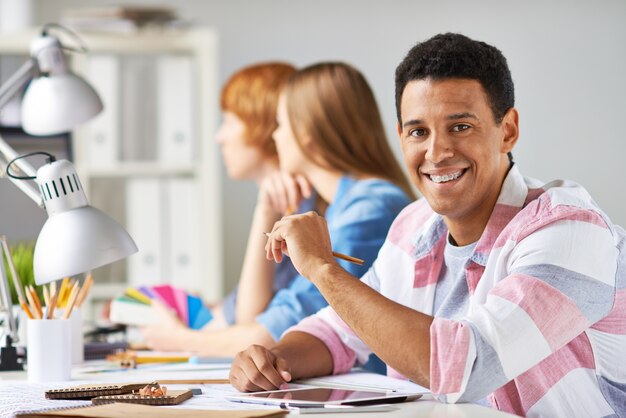 Bel studente che lavora con una matita e un touchpad