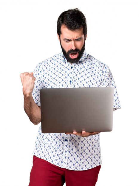 Bel uomo brunetta con la barba con il computer portatile