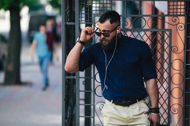 Bel uomo che tocca gli occhiali da sole