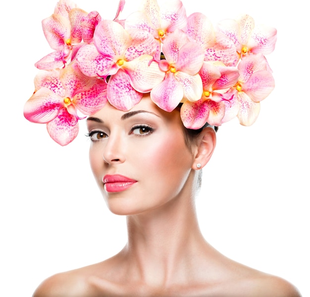 Bel viso di giovane donna graziosa con pelle sana e fiori rosa isolati su bianco