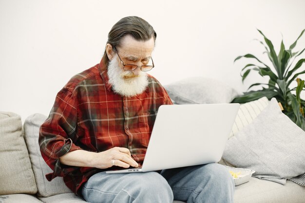 Bell'uomo anziano. Lavorare con il laptop. Seduto sul divano.