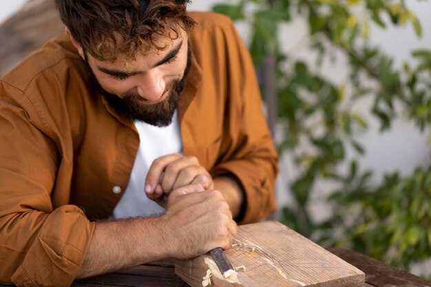 Bell'uomo che incide su legno all'aperto