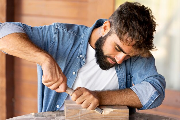 Bell'uomo che incide su legno all'aperto