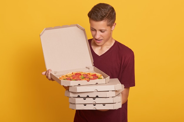 bell'uomo che indossa una maglietta casual bordeaux, con in mano una pila di scatole per pizza