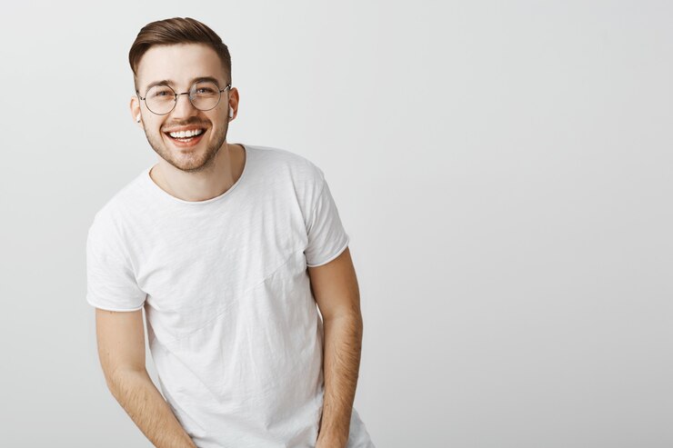 Foto gratuito bell'uomo con denti bianchi, sorridente e con gli occhiali sul muro grigio