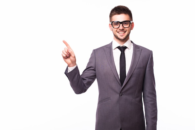 Bell'uomo d'affari con gli occhiali in piedi con la mano in tasca in un modo e indicando da parte felice su sfondo bianco studio