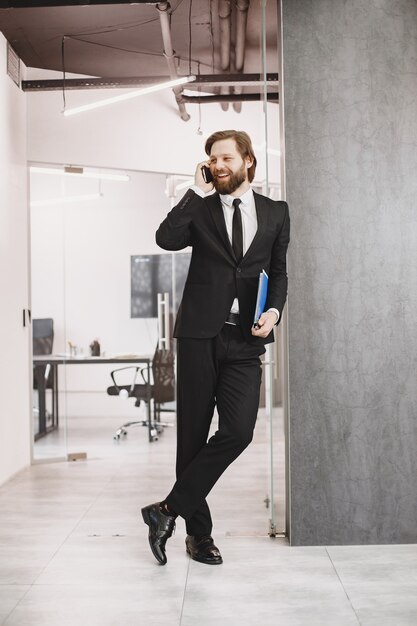 Bell'uomo in abito nero. Uomo d'affari con il telefono cellulare.