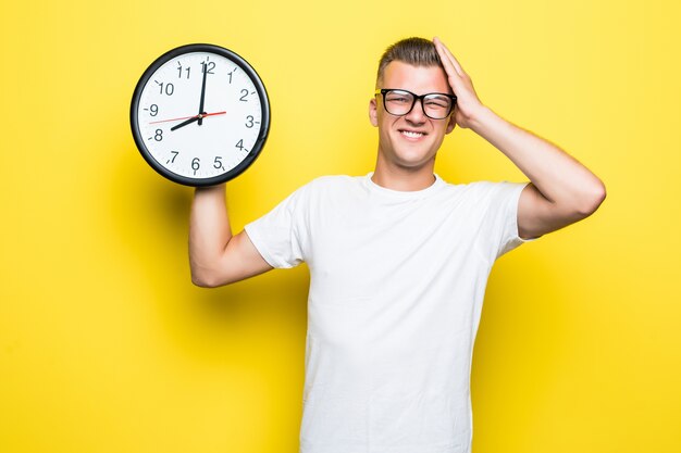 Bell'uomo in maglietta bianca e occhiali trasparenti tiene un grande orologio in una mano