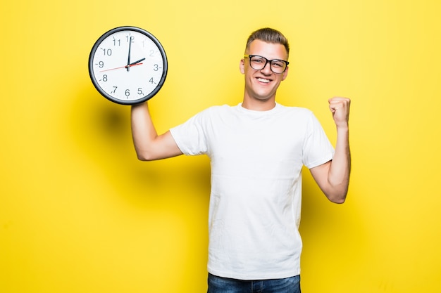 Bell'uomo in maglietta bianca e occhiali trasparenti tiene un grande orologio in una mano