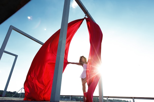 Bella ballerina bruna con tende rosse in posa sul tetto