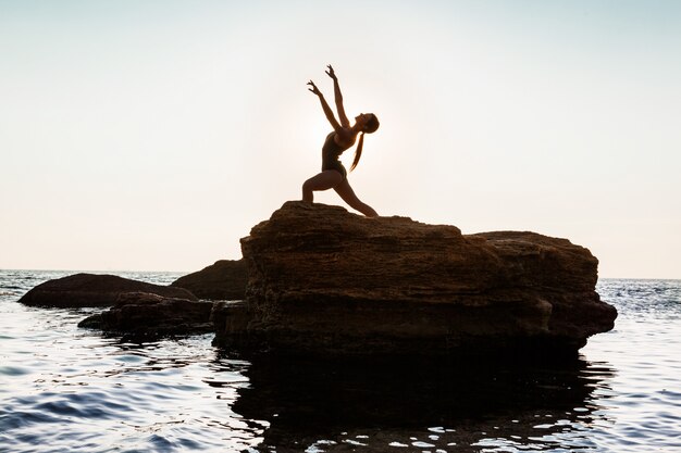 Bella ballerina danza, posa su roccia in spiaggia, vista sul mare.