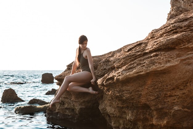Bella ballerina danza, posa su roccia in spiaggia, vista sul mare.