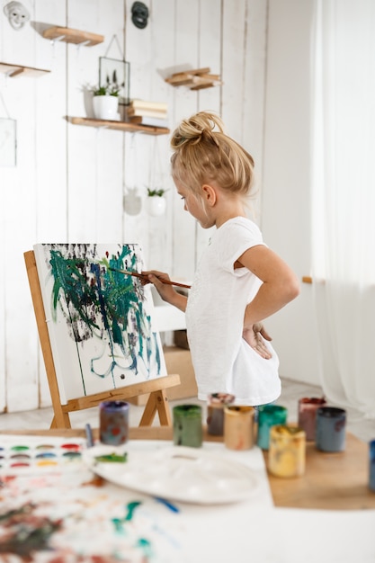 bella bambina europea che ha concentrato lo sguardo mentre si lavora sulla sua foto in sala d'arte.