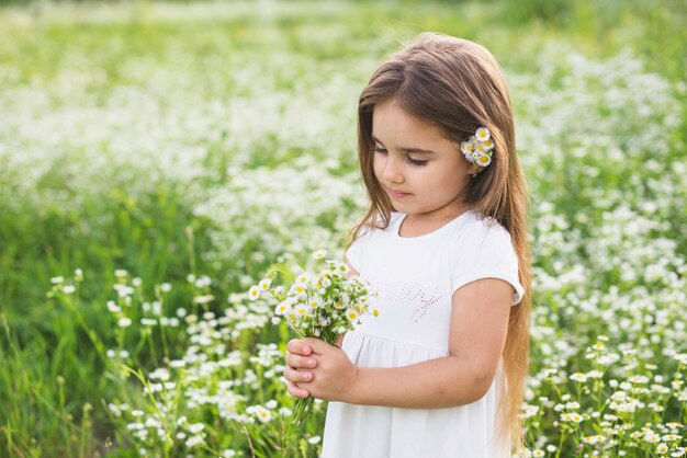 Bella bambina in abito bianco, raccogliendo fiori bianchi