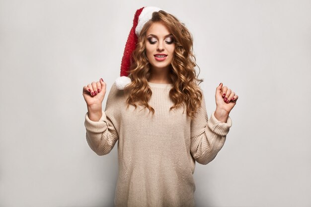 Bella bionda positiva in un maglione e berretto festivo