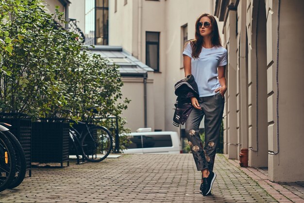 Bella bruna alla moda in un abbigliamento elegante passeggiando per la strada.