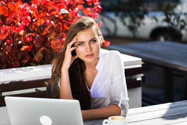 Bella bruna lavora con laptop fuori