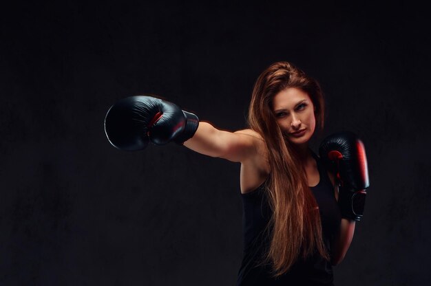 Bella bruna pugile durante gli esercizi di boxe, incentrata sul processo con un viso serio concentrato.