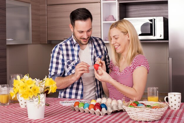 Bella coppia che sorride e dipinge le uova di Pasqua