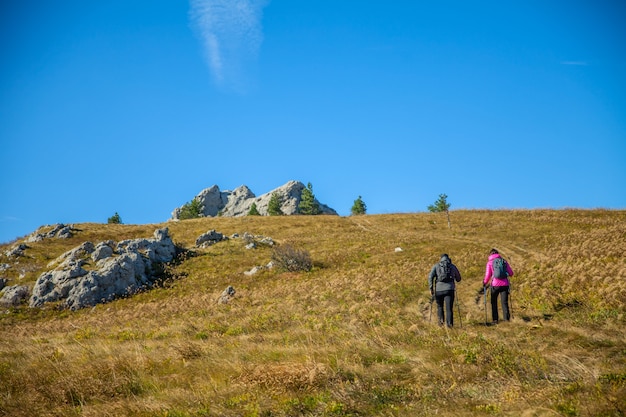 Bella coppia di turisti che scalano le montagne rocciose slovene sotto il cielo blu